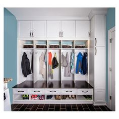 a white closet filled with lots of coats and shoes next to a blue painted wall