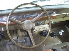 the steering wheel and dashboard of an old car with wood paneling on the dash