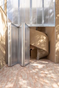 an open door leading into a room with a spiral staircase in the center and brick flooring