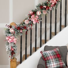 a christmas garland on the banister next to a stair case with candy canes and candies