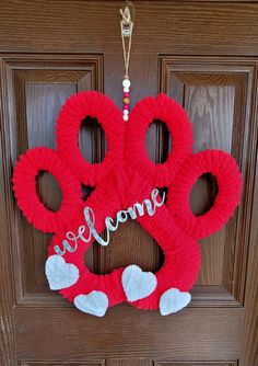 a red wreath with the words welcome hanging on a door