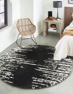 a black and white rug in a bedroom next to a bed with a wooden chair