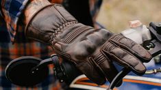 a close up of a person's brown leather gloves on a motorbike