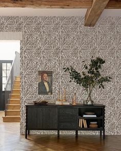 a living room with wooden floors and wallpaper on the walls, along with a plant in a vase