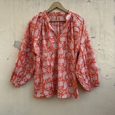 This divine cotton blouse is as light as can be. With the most romantic billowed sleeves, elastic cuffs, and two optional ties at the front. The flowing fabric features a sweet floral classic Indian Buti block print in cinnamon on soft white cotton. A timeless feminine piece. Material ~ 100% Cotton. Depending on each individual, some find the material sheer.  Garment Care ~ We recommend a gentle, cold water hand wash using natural detergents, and hang drying in the shade. Handcrafted garments ar Orange Cotton Blouse For Summer, Cotton Floral Print Balloon Sleeve Top, Floral Print Balloon Sleeve Cotton Top, Bohemian Tops With Elastic Sleeves For Fall, Summer Orange Cotton Blouse, Bohemian Top With Elastic Sleeves For Fall, Fall Bohemian Top With Elastic Sleeves, Billowy Balloon Sleeve Blouse With Floral Print, Summer Peasant Top With Balloon Sleeves And Relaxed Fit