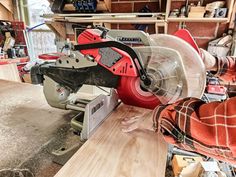 a red and black circular saw sitting on top of a wooden table