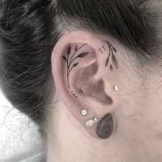 a woman's left ear with black and white leaves on it, behind the ear