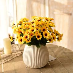 a white vase filled with yellow flowers on top of a table