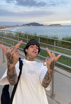 a young man with tattoos on his arms making the v sign while standing in front of a railing