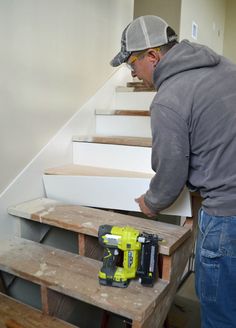 a man is working on some stairs with a driller and screwdriver in his hand