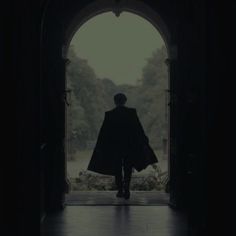 a man in a cape walking into an archway