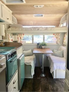 the inside of a camper with a table, stove and sink in front of it