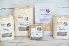 four bags of organic whole wheat next to each other on a white table with wood planks in the background