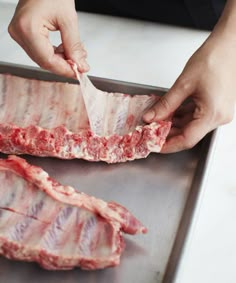 a person cutting up meat on top of a metal tray