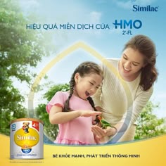 a woman and girl are playing with an insect in front of a poster for simila