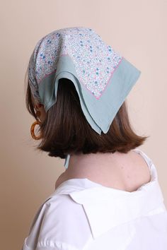 the back of a woman's head wearing a white shirt and blue bandana