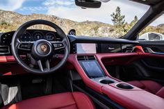 the interior of a sports car with red leather seats and steering wheel, mountains in the background