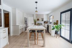 a kitchen with two stools and a table in front of an open glass door