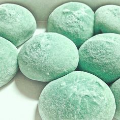 several round green powdered donuts sitting in a white box on top of a table