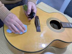 a person is cleaning an acoustic guitar with a cloth and sponge on the top of it