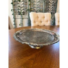 a silver plate sitting on top of a wooden table in front of a white chair