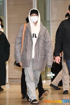 a man wearing a face mask while walking through an airport terminal with other people in the background