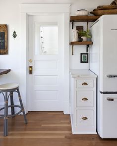 a white kitchen with an open door and stools in front of the counter top