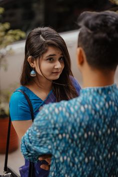 a woman talking to a man in front of a car