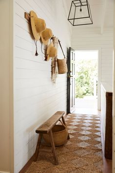 a wooden bench sitting in the middle of a hallway next to a wall with hats hanging on it