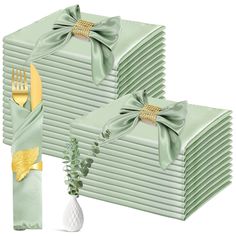 a stack of green napkins with gold forks and knives on them, sitting next to each other