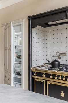 an old fashioned stove in the middle of a kitchen with black and white tiles on the wall