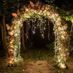 an archway decorated with flowers and butterflies is lit up by fairy lights in the dark