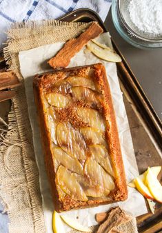 an apple pie is sitting on a baking sheet next to some cinnamon sticks and apples