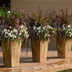 three planters with flowers in them sitting on the ground