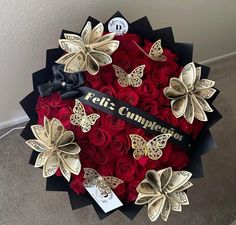 a bouquet of red roses in a black box with gold butterflies on the front and side