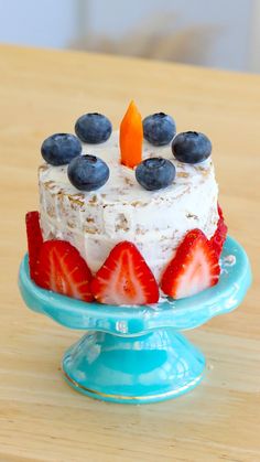 a cake with strawberries and blueberries on it sitting on top of a table