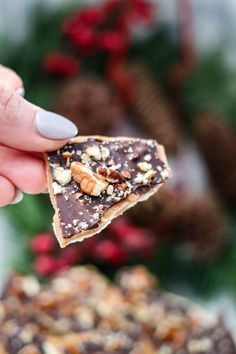 a person holding a piece of food in their hand with christmas decorations in the background