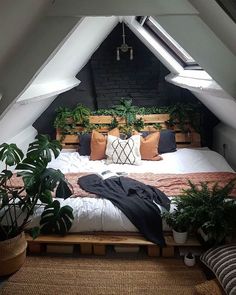 an attic bedroom with plants and pillows on the bed