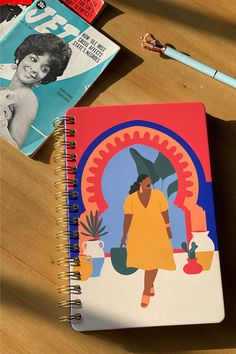 a spiral notebook with an image of a woman holding an umbrella on top of it