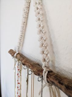 several necklaces hanging from a wooden branch on the wall with chains attached to it