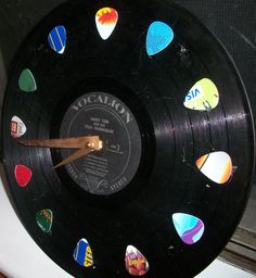 a clock made out of an old record with various stickers on the front and sides