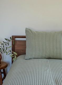 a green and white checkered comforter on a bed next to a potted plant