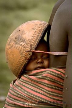 a baby wrapped in a blanket with a helmet on it's head is being held by an adult