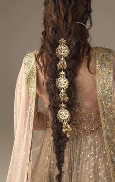 the back of a woman's dress with long hair in braids and beads