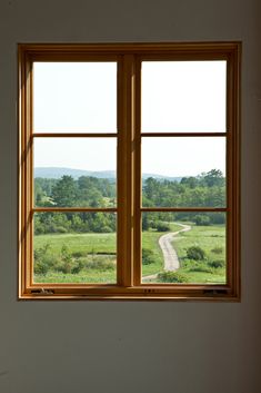 an empty room with two windows looking out on a country road and trees in the distance