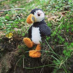 a crocheted penguin sitting in the grass