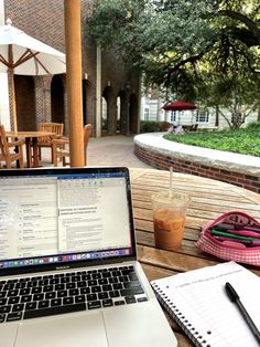 an open laptop computer sitting on top of a wooden table next to a cup of coffee