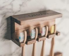 three toothbrushes in wooden holder on marble wall