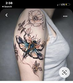 a woman's arm with flowers and a butterfly tattoo on her left upper arm