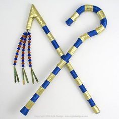 two sticks are made out of gold and blue strips, with beads on each end